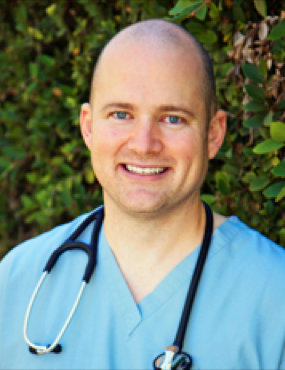 A bald man wearing scrubs and a stethoscope around his neck