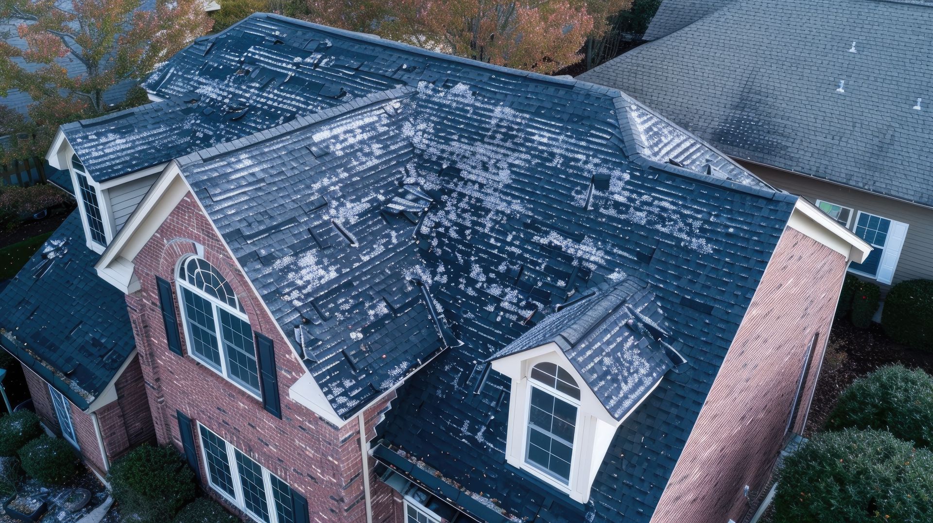 An aerial view of a brick house with a black roof.