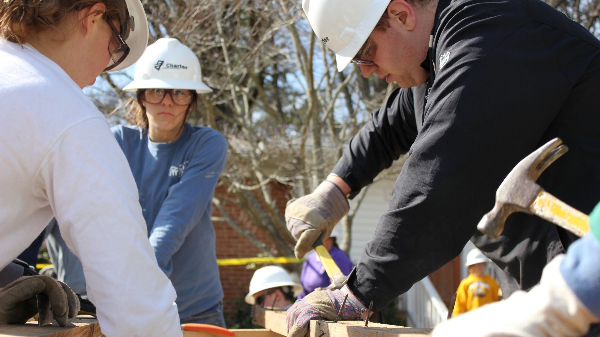 A group of people wearing hard hats are working on a wooden structure.