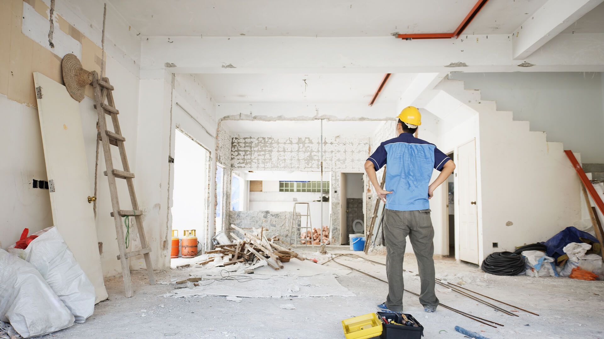 A man in a hard hat is standing in a room under construction.