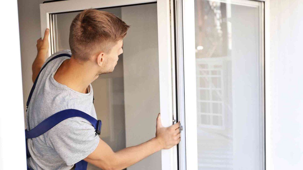 A man is installing a window in a house.