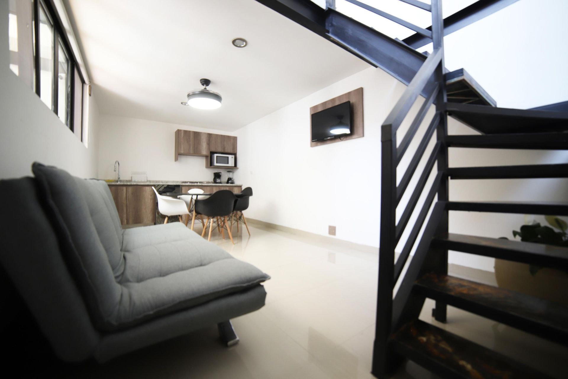 Una sala de estar con un sofá y escaleras que conducen al segundo piso.