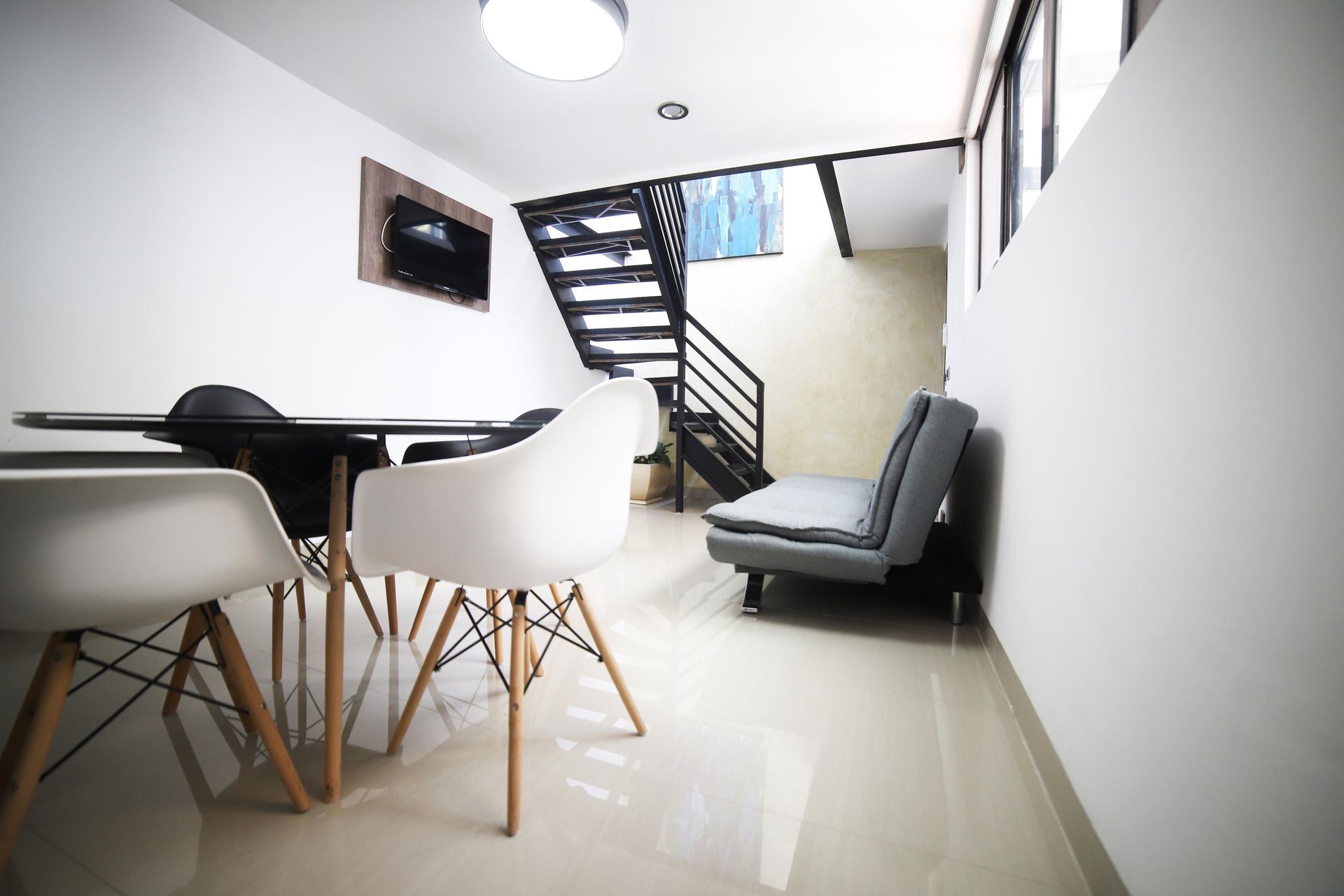 Una sala de estar con sofá, mesa, sillas y escaleras.
