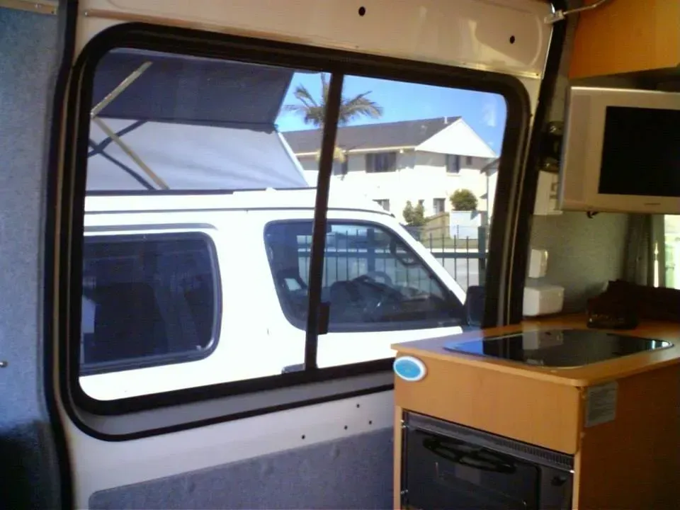 A white van is parked in the back of a camper van