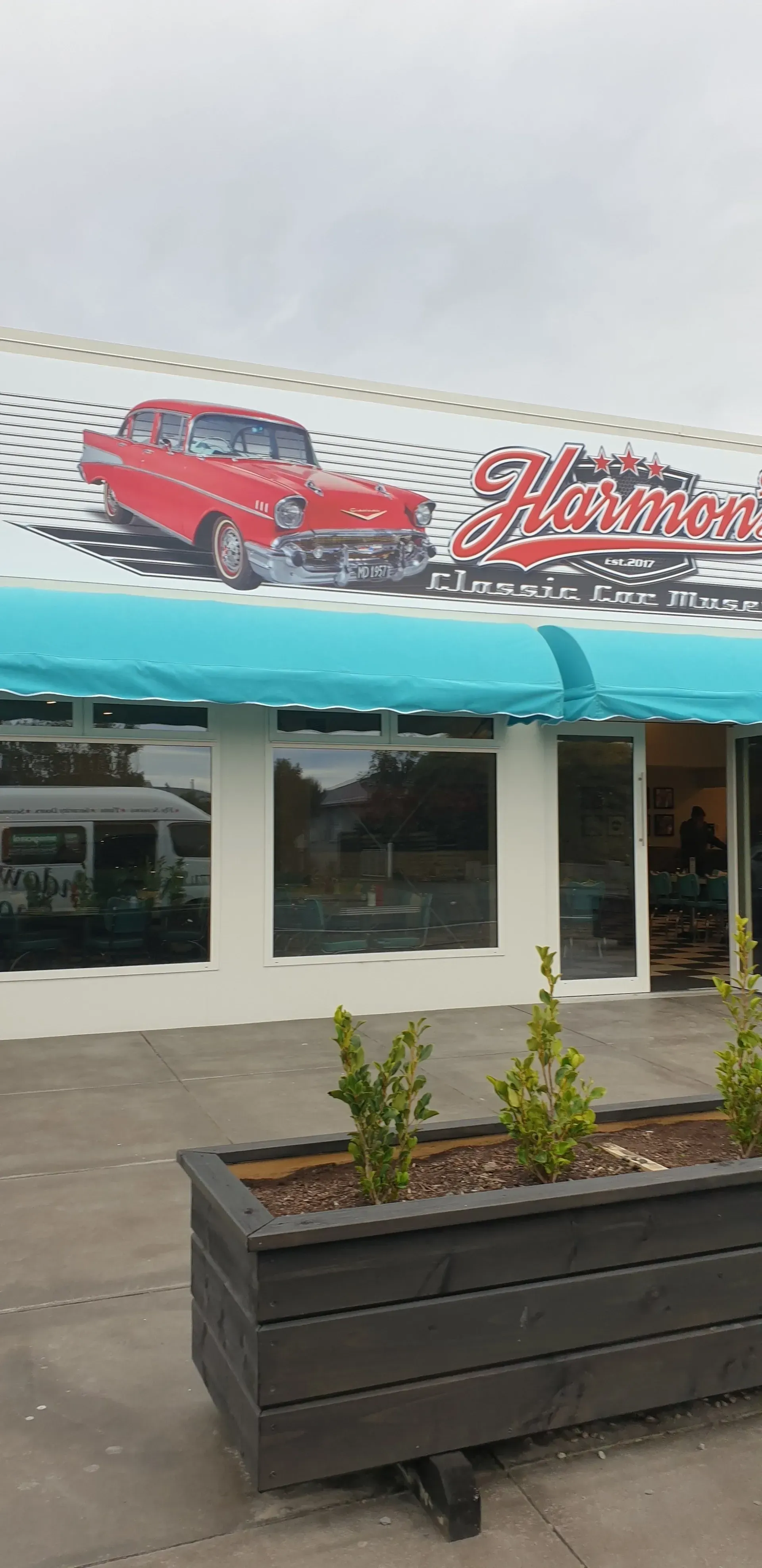 A red car is on the side of a building with a blue awning.
