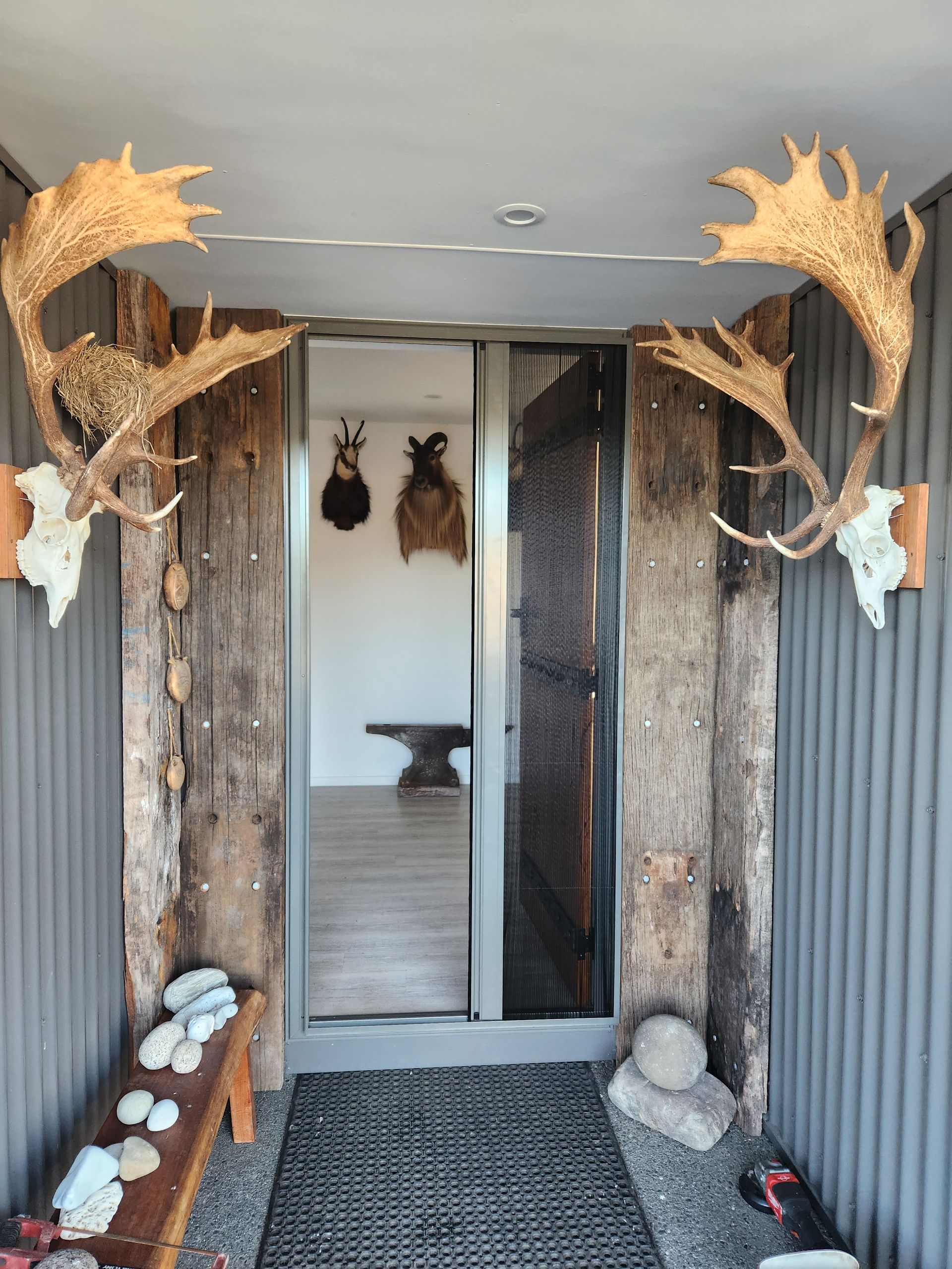 A close up of a sliding screen door with a window in the background.
