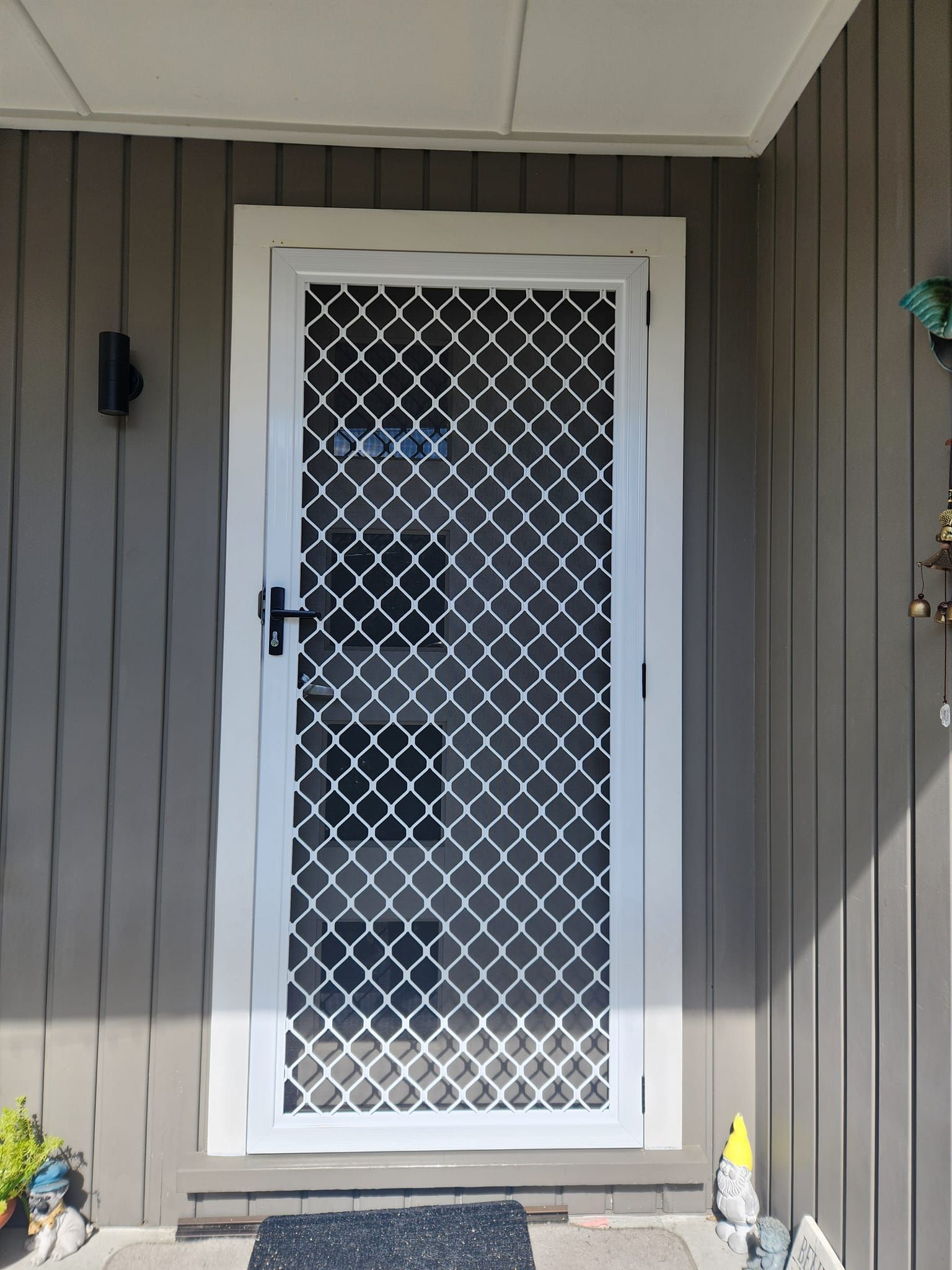 A white door with a black and white checkered pattern on it is on the side of a house.