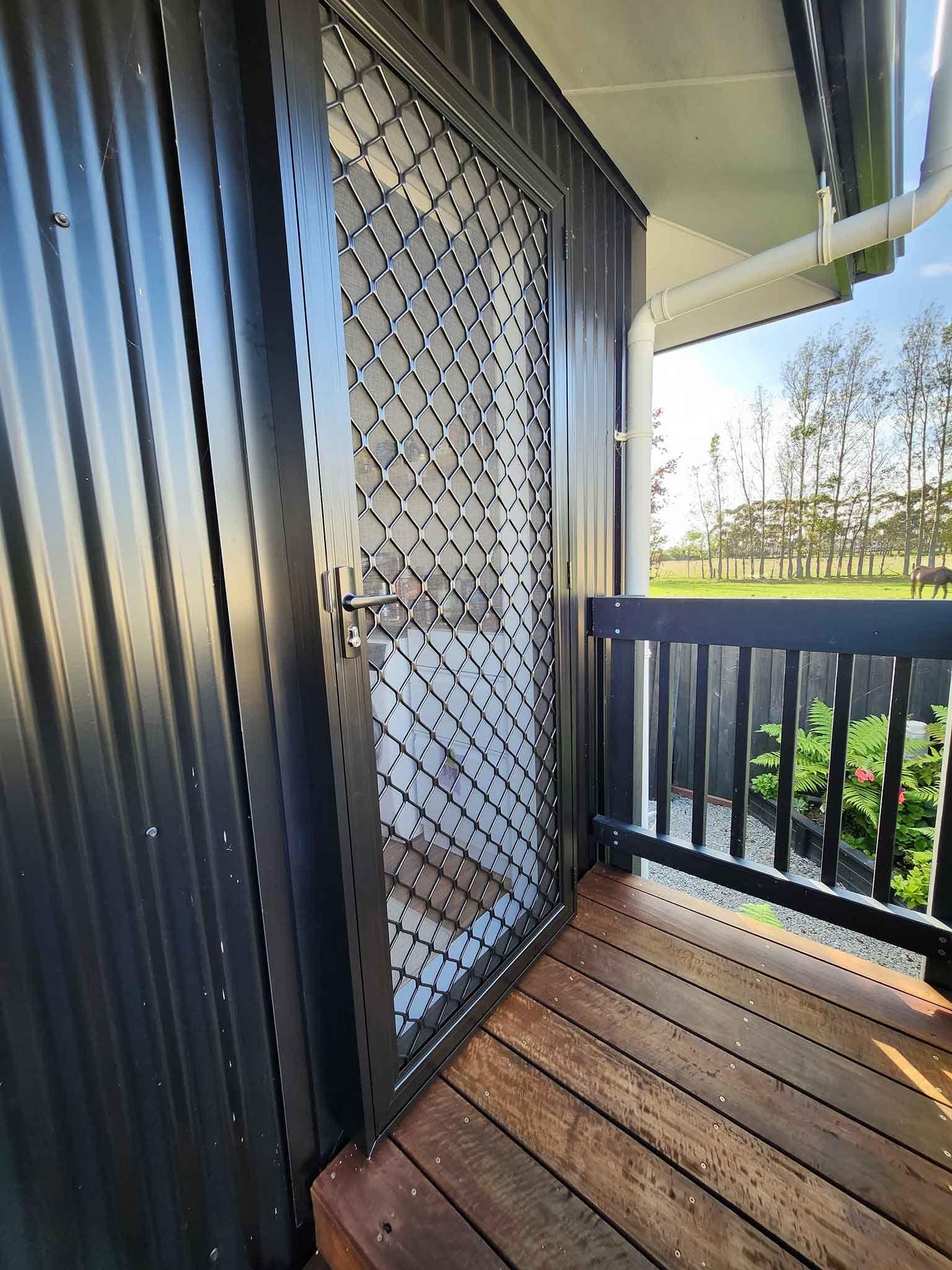 A balcony with a screen door and a wooden deck.
