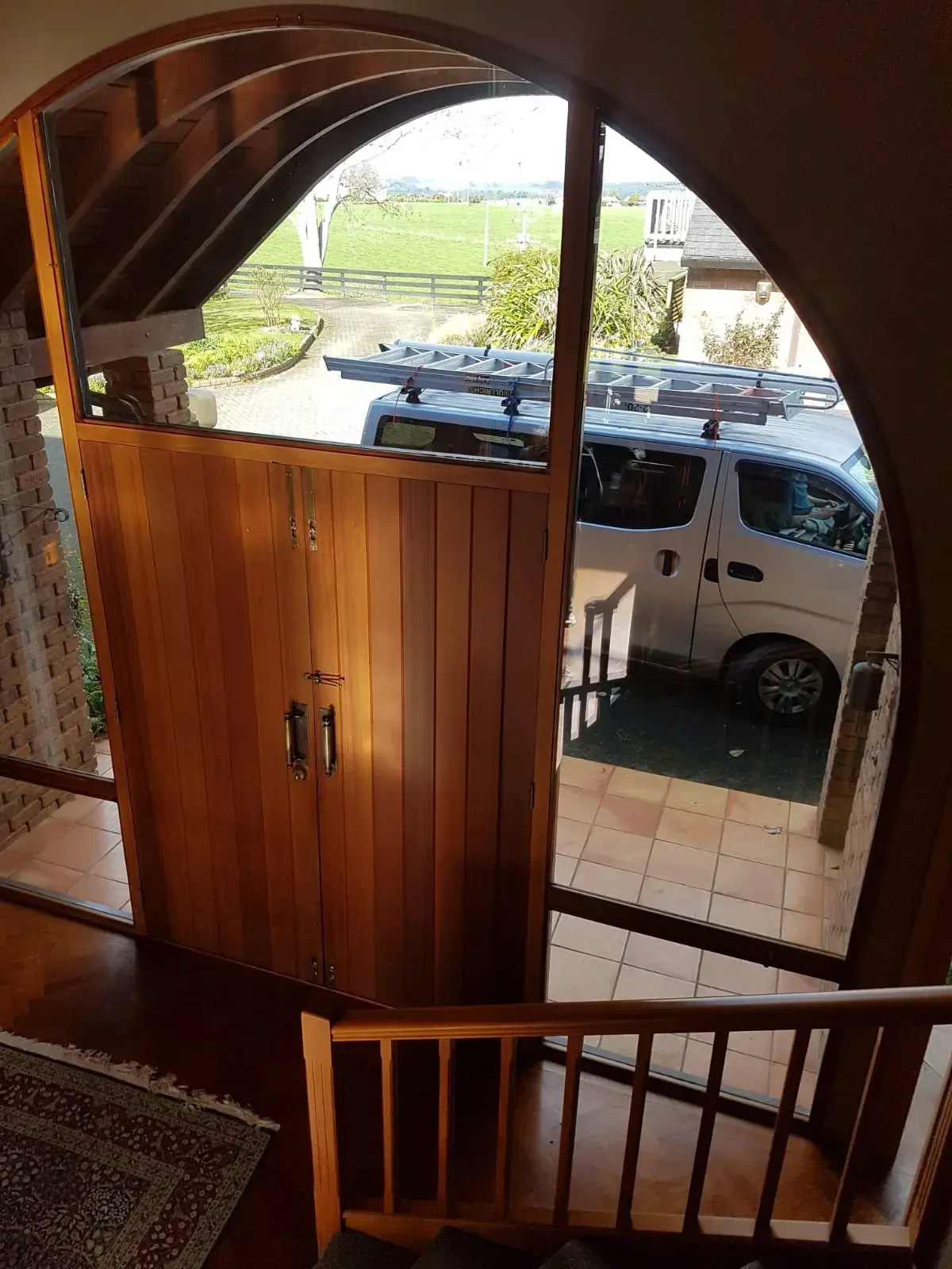 A white van is parked in front of a wooden door in a house.