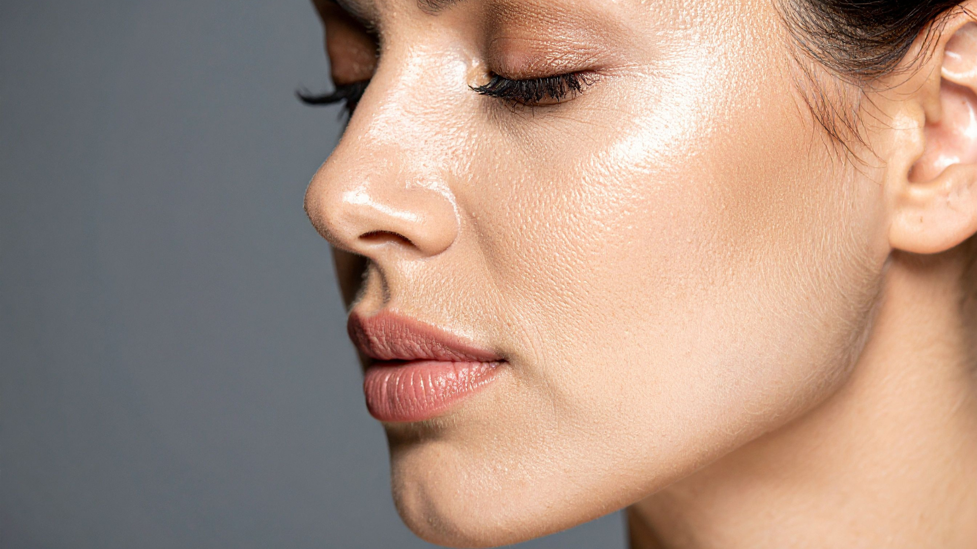 Close-up profile of a woman with closed eyes against a gray background
