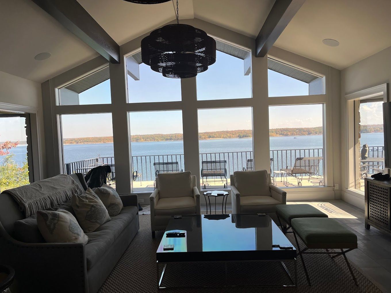 A living room with a couch , chairs , coffee table and large windows overlooking a lake.