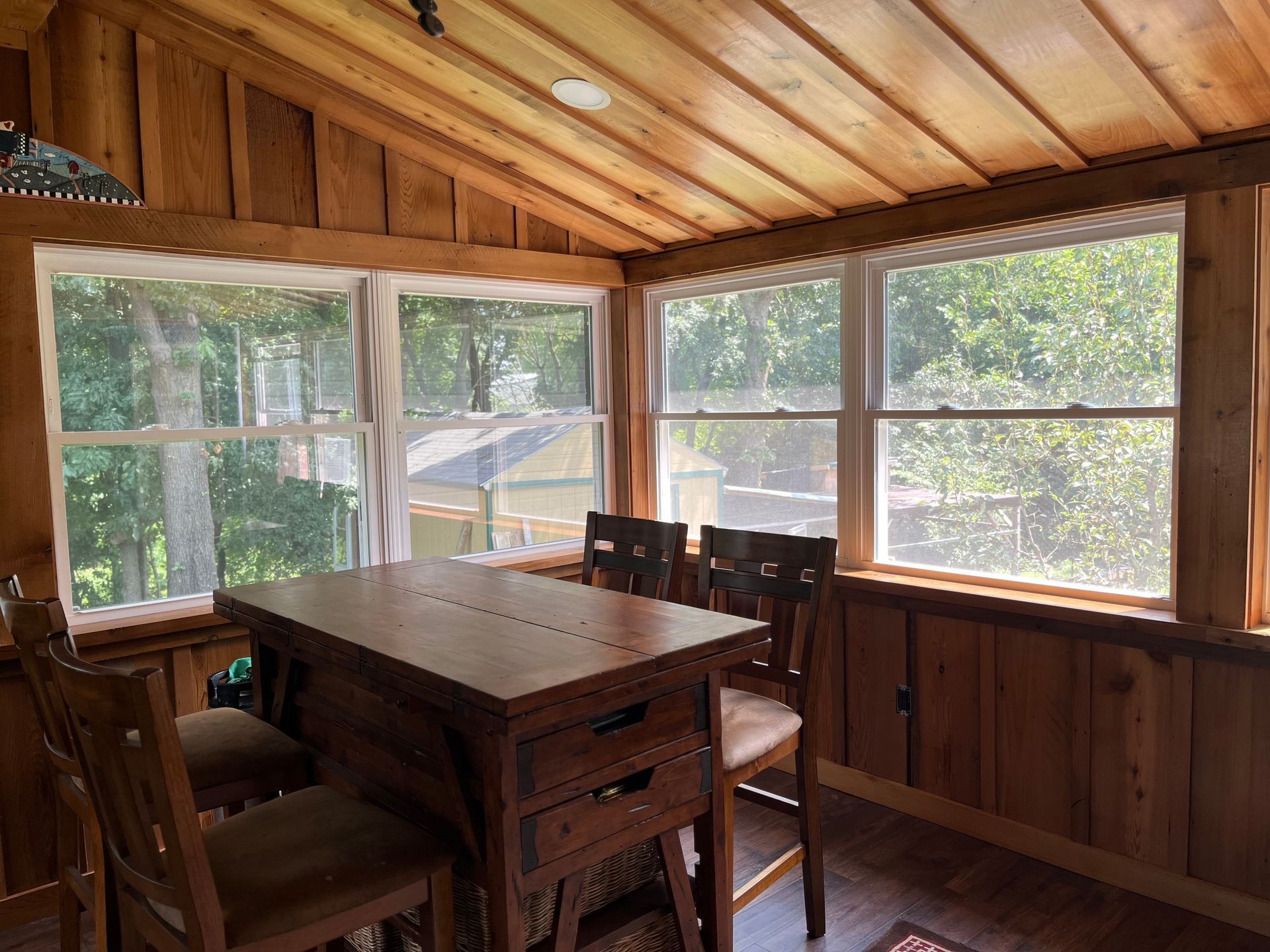 There is a table and chairs in the room with a lot of windows.