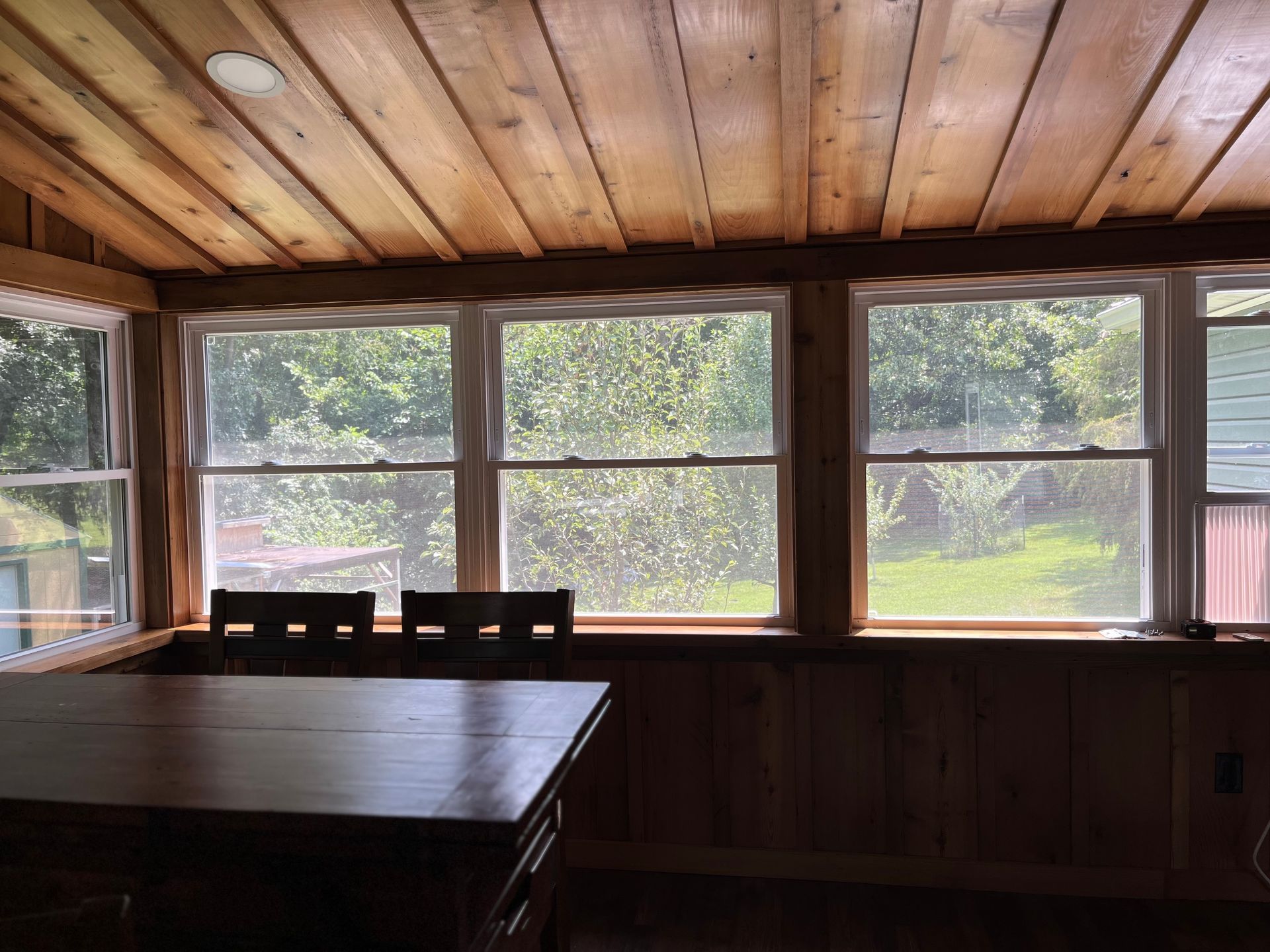 A room with a table and chairs and lots of windows