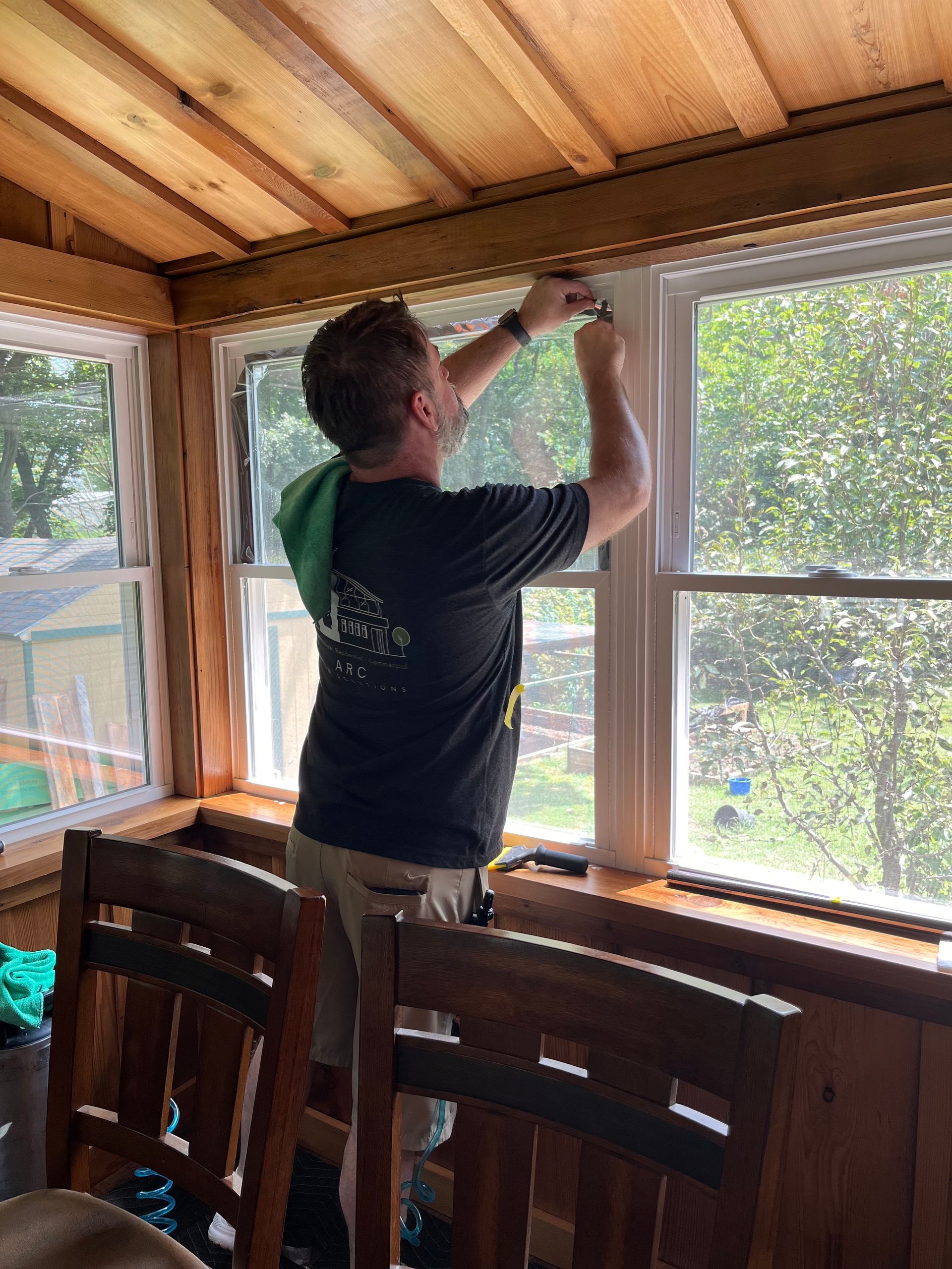 A man is standing in front of a window in a room.