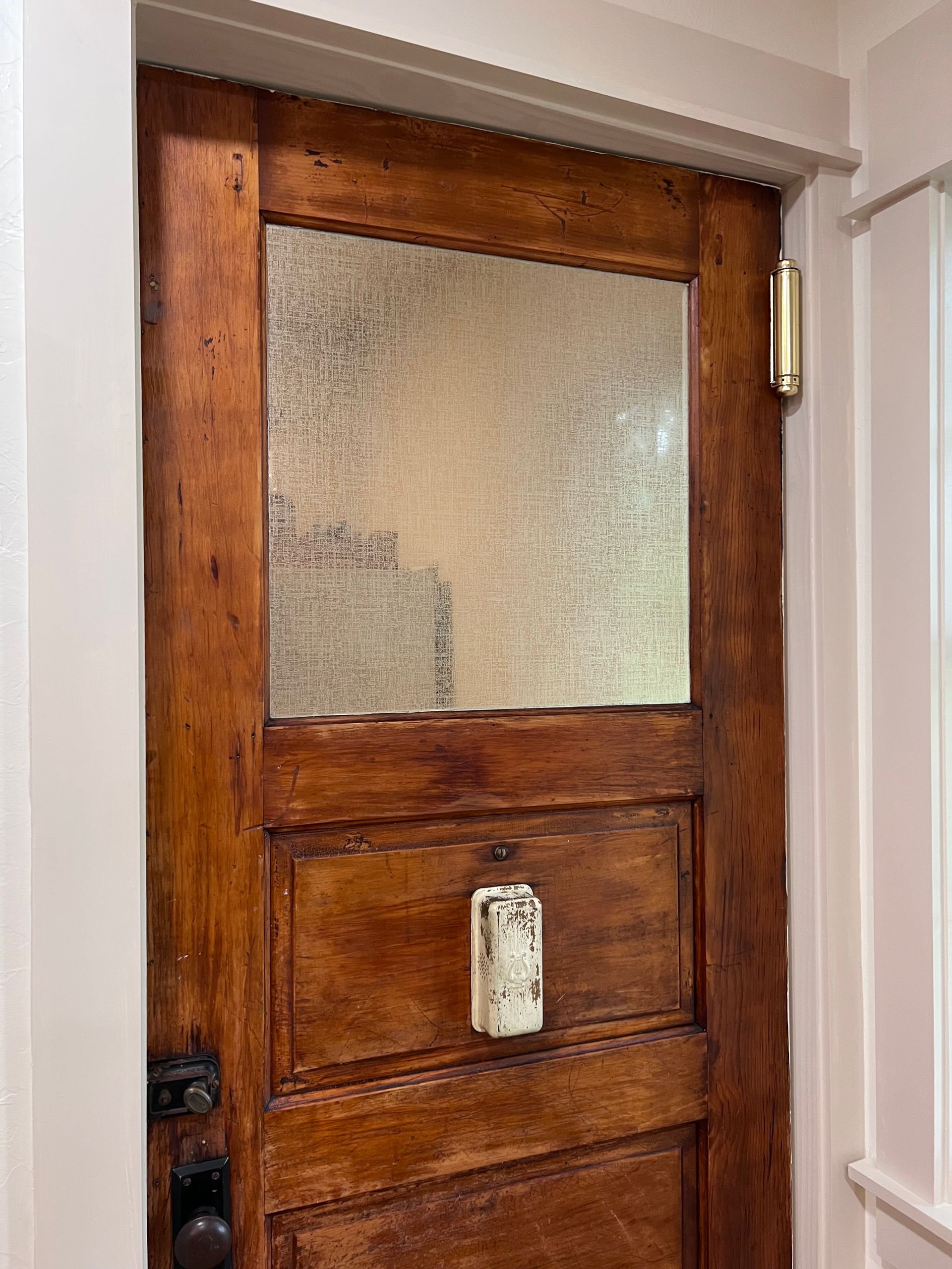 A wooden door with a glass window and a white handle.
