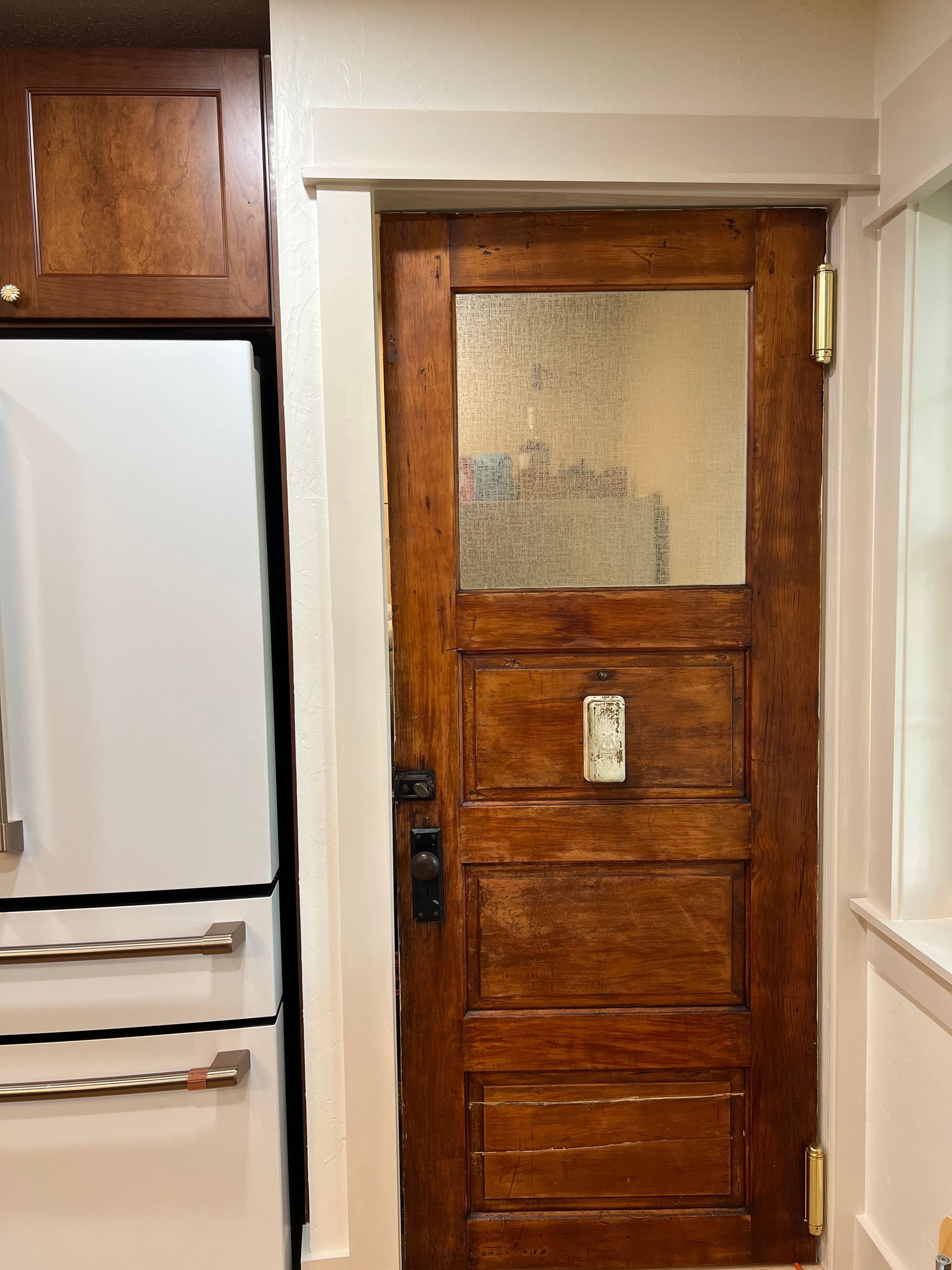 A kitchen with a wooden door and a white refrigerator