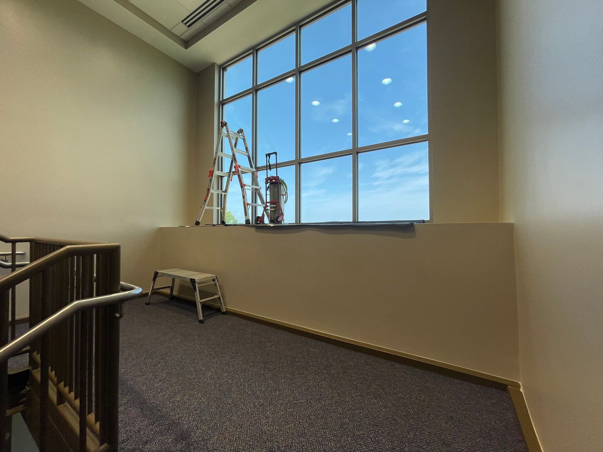 A ladder is sitting in front of a large window in a building.