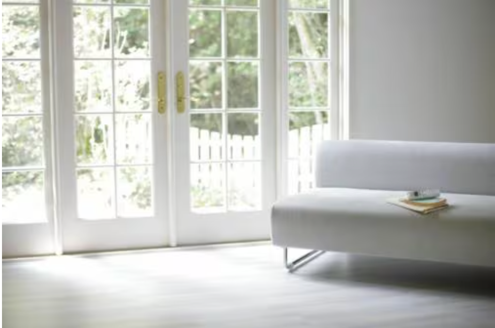 A white couch is sitting in a living room next to a window.