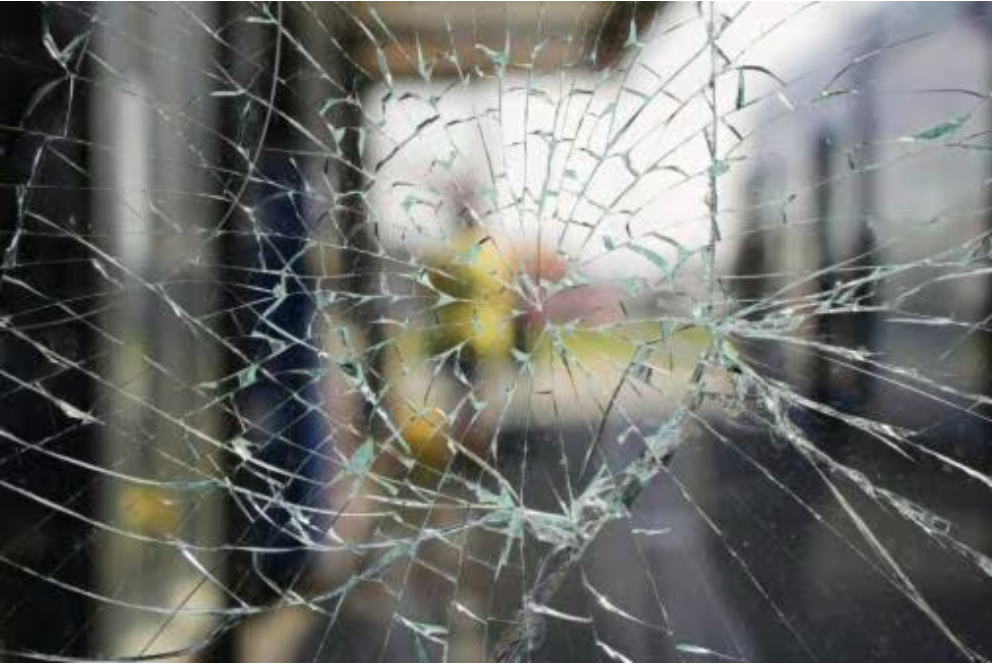 A close up of a broken glass window with a blurry background.