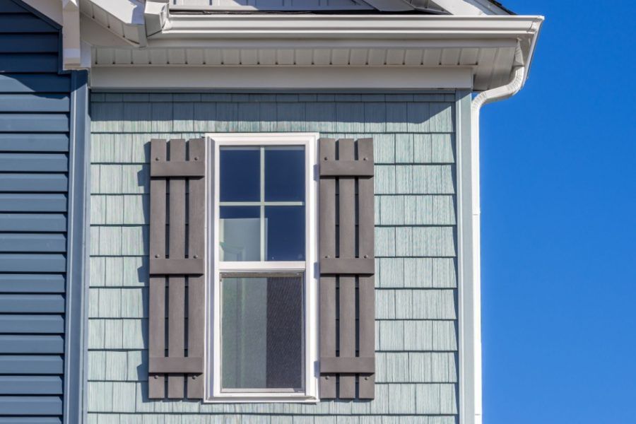 A close up of a window with shutters on a house.