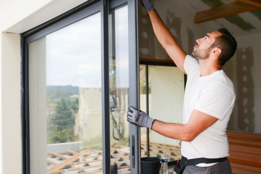 A man is installing a sliding glass door in a house.