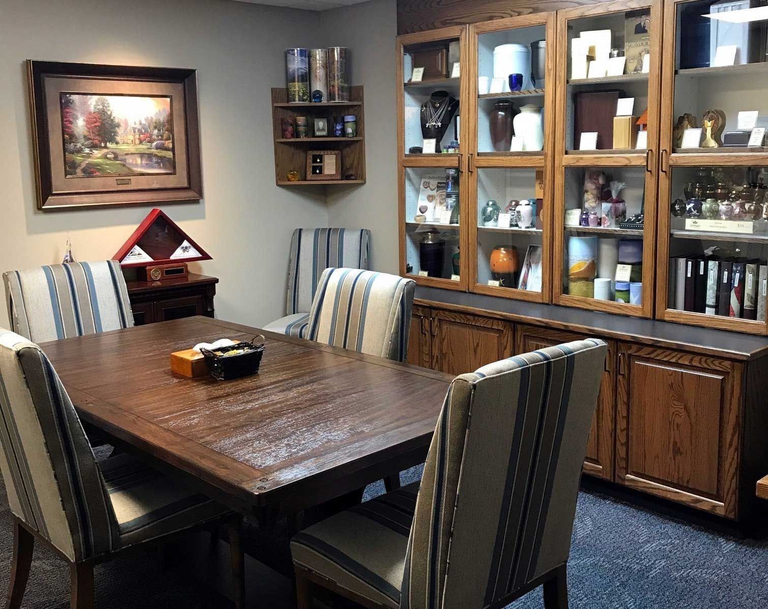 A meeting room with a wooden table, chairs, and display cabinets filled with various objects.