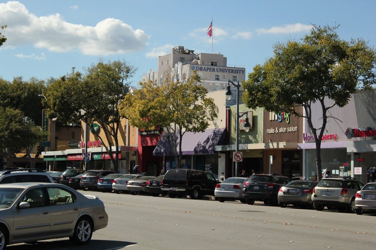 A row of cars are parked on the side of a street