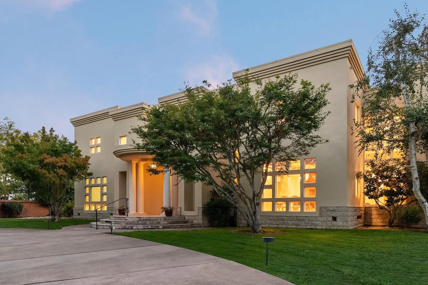 A large house with lots of windows and trees in front of it
