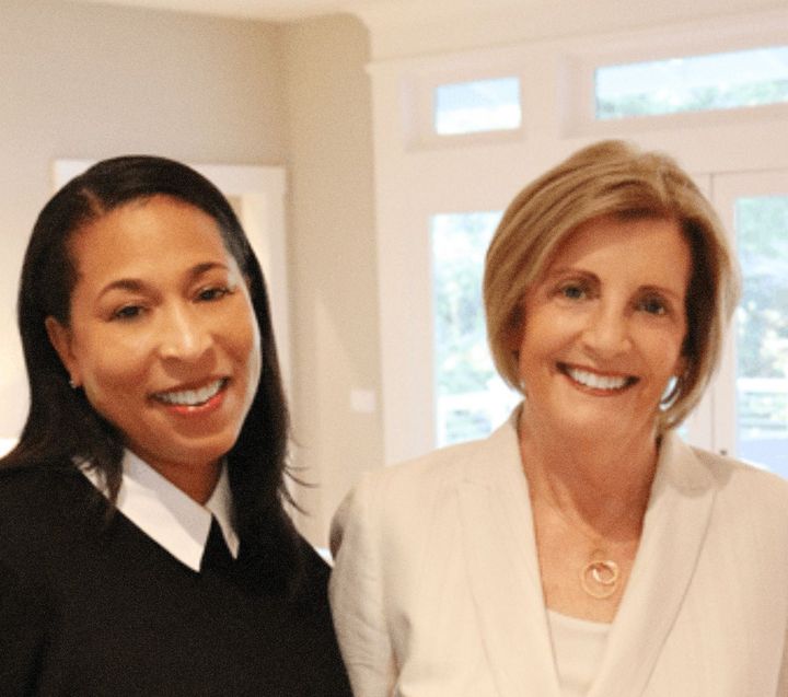 Two women are posing for a picture and smiling for the camera