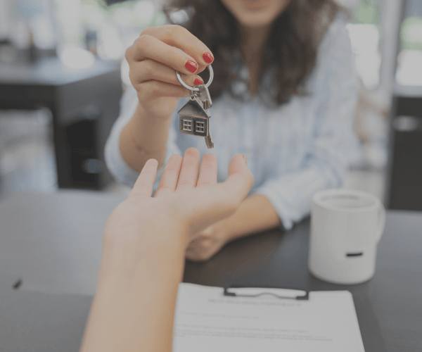 A woman is giving a house key to another person