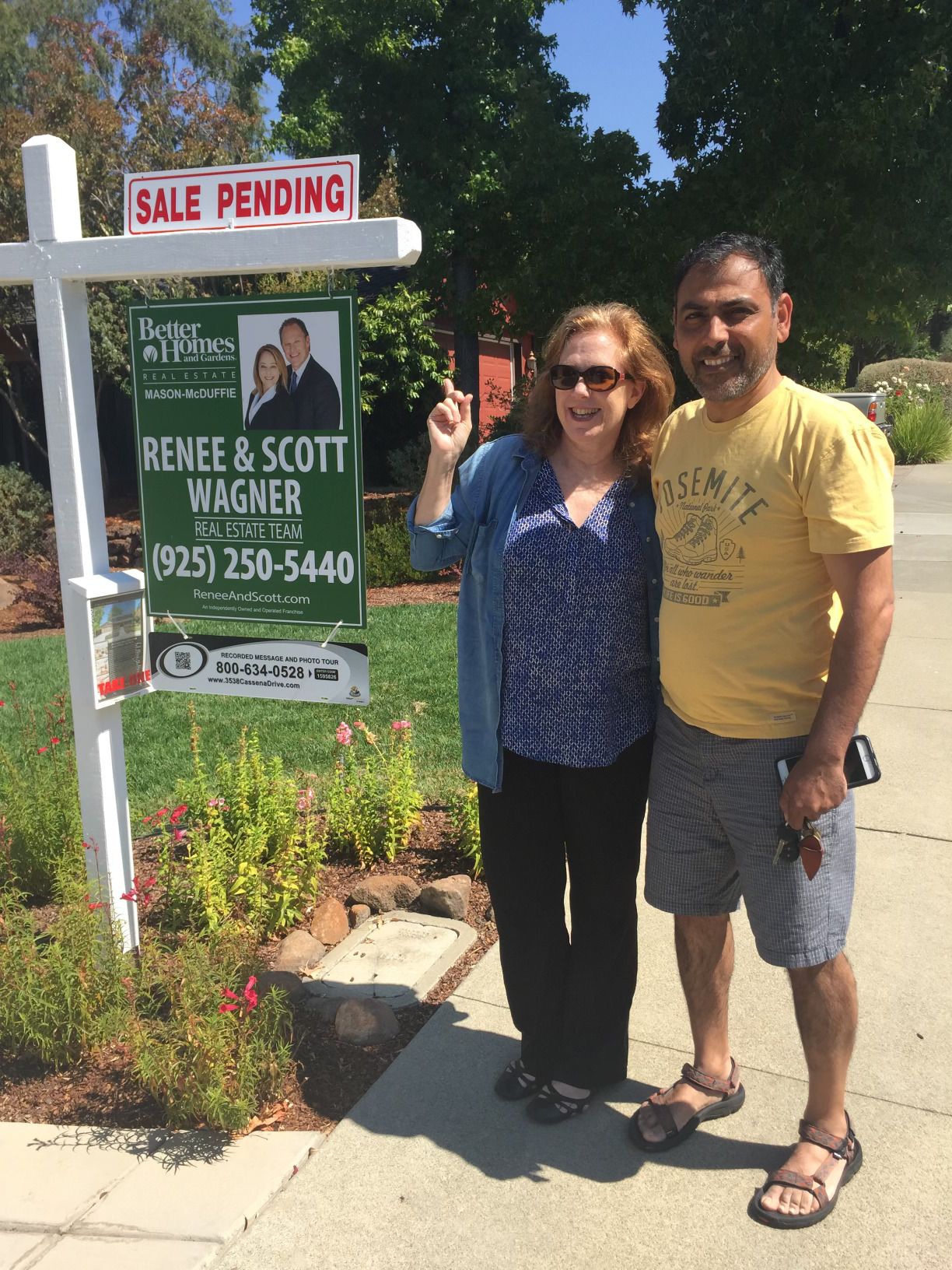 A man and woman standing in front of a renee & scott wagner real estate sign
