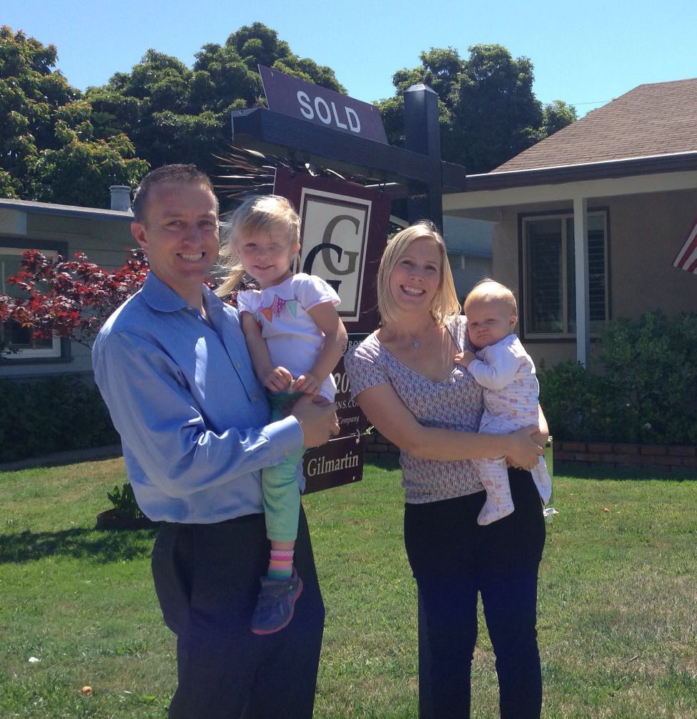A family standing in front of a sold sign