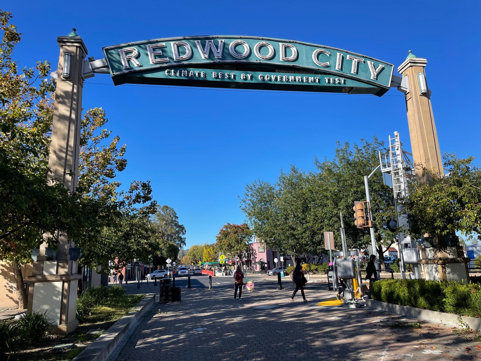 People are walking under a sign that says redwood city