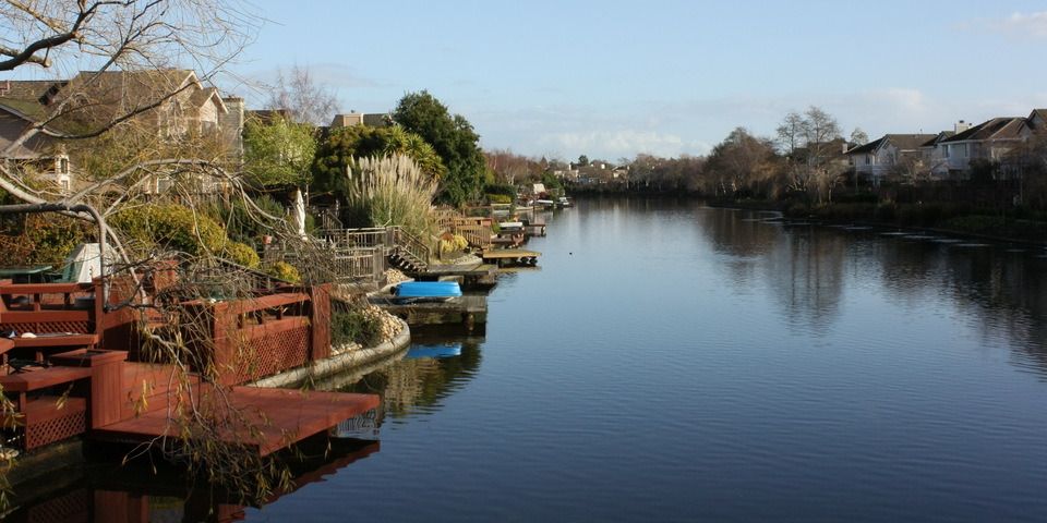 A river surrounded by houses and trees on a sunny day.