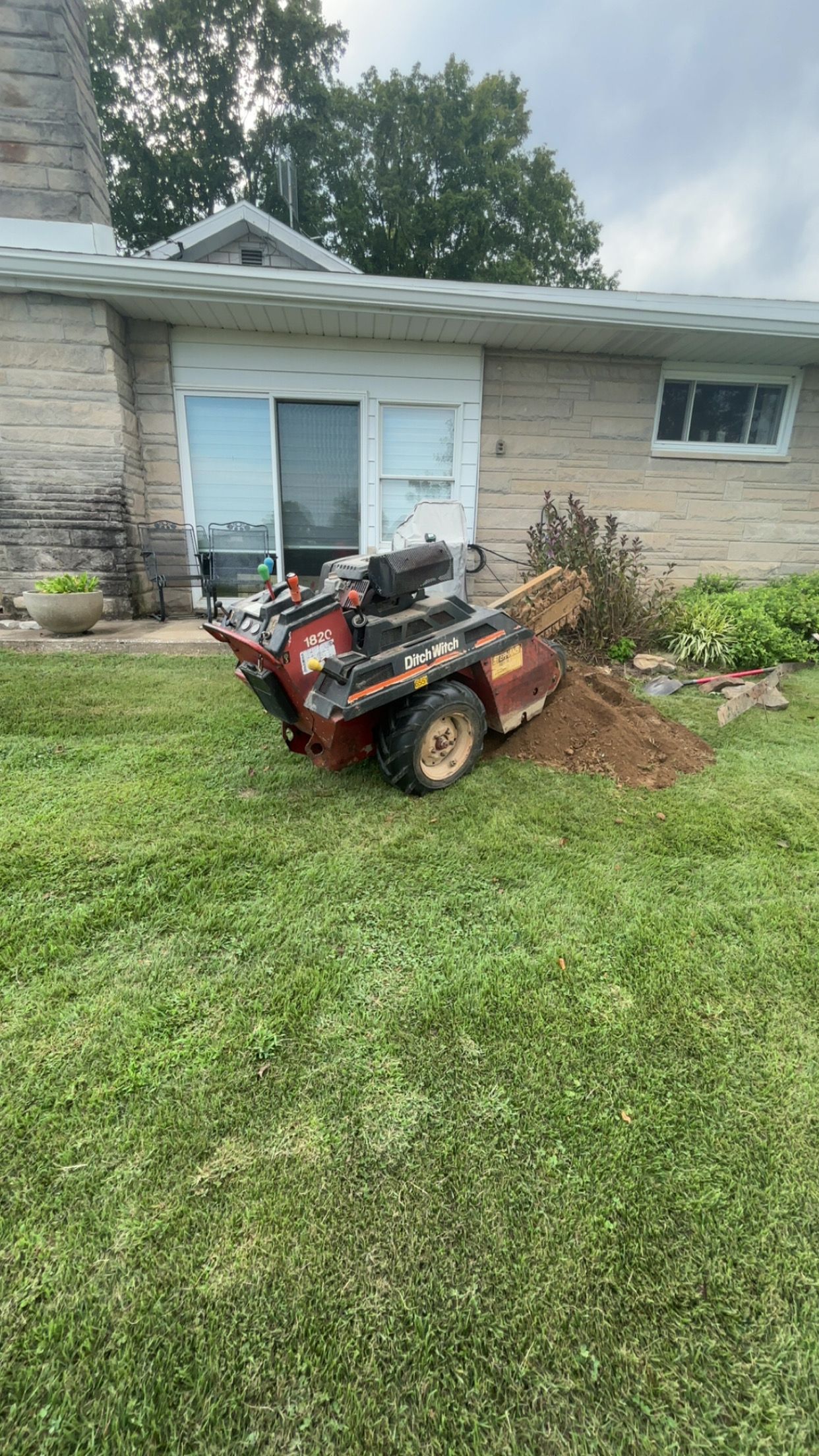 A small tree stump grinder sitting on a grassy yard near a house.