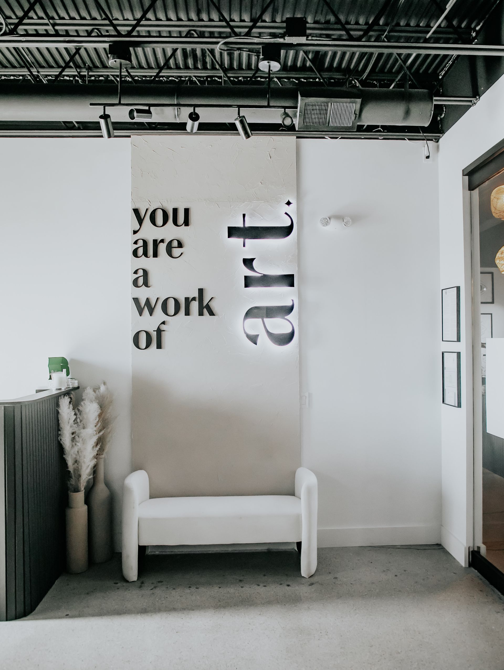 A room with a bench and a sign on the wall that says `` you are a work of art ''.