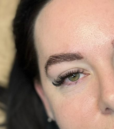 Close-up of a person's eye and eyebrow with lash extensions and microbladed brow.