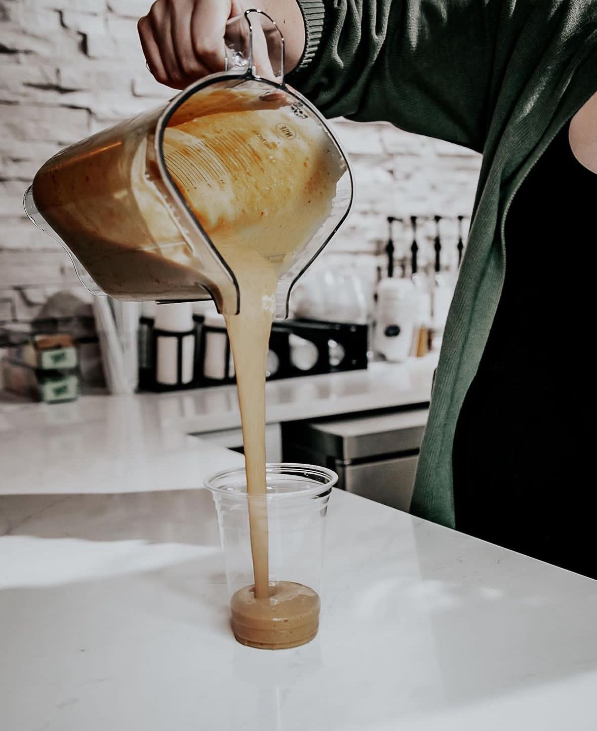A woman in a white robe is smiling in a bathroom.
