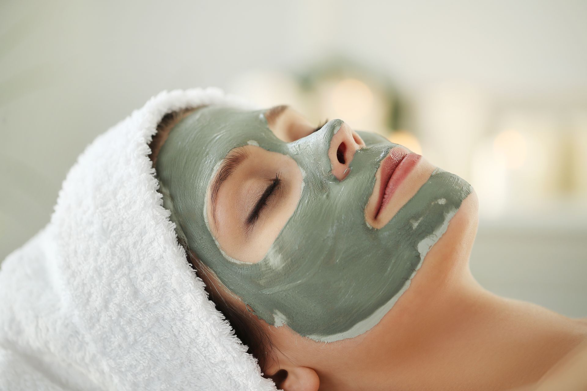 A woman is laying down with a clay mask on her face.