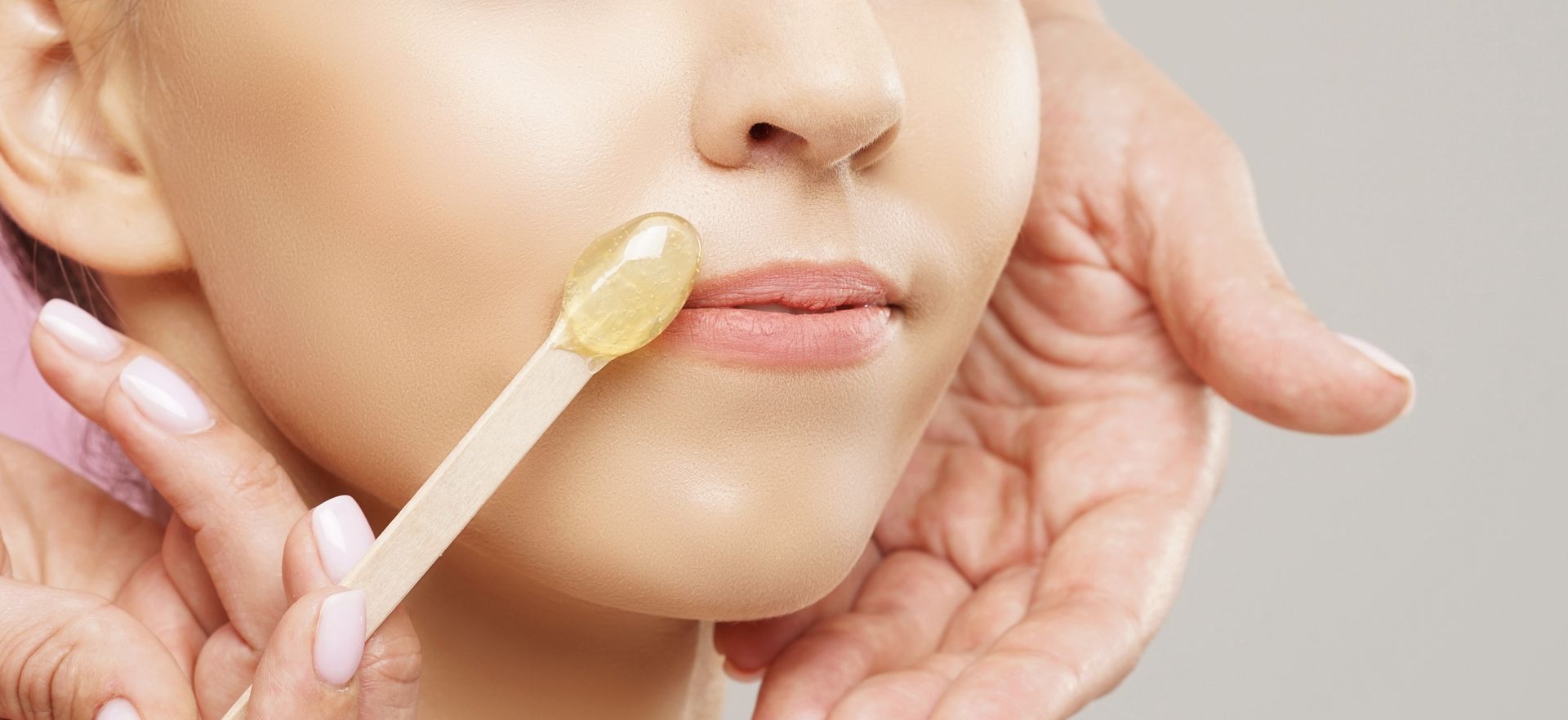 A woman is getting her lips waxed with a wax stick.