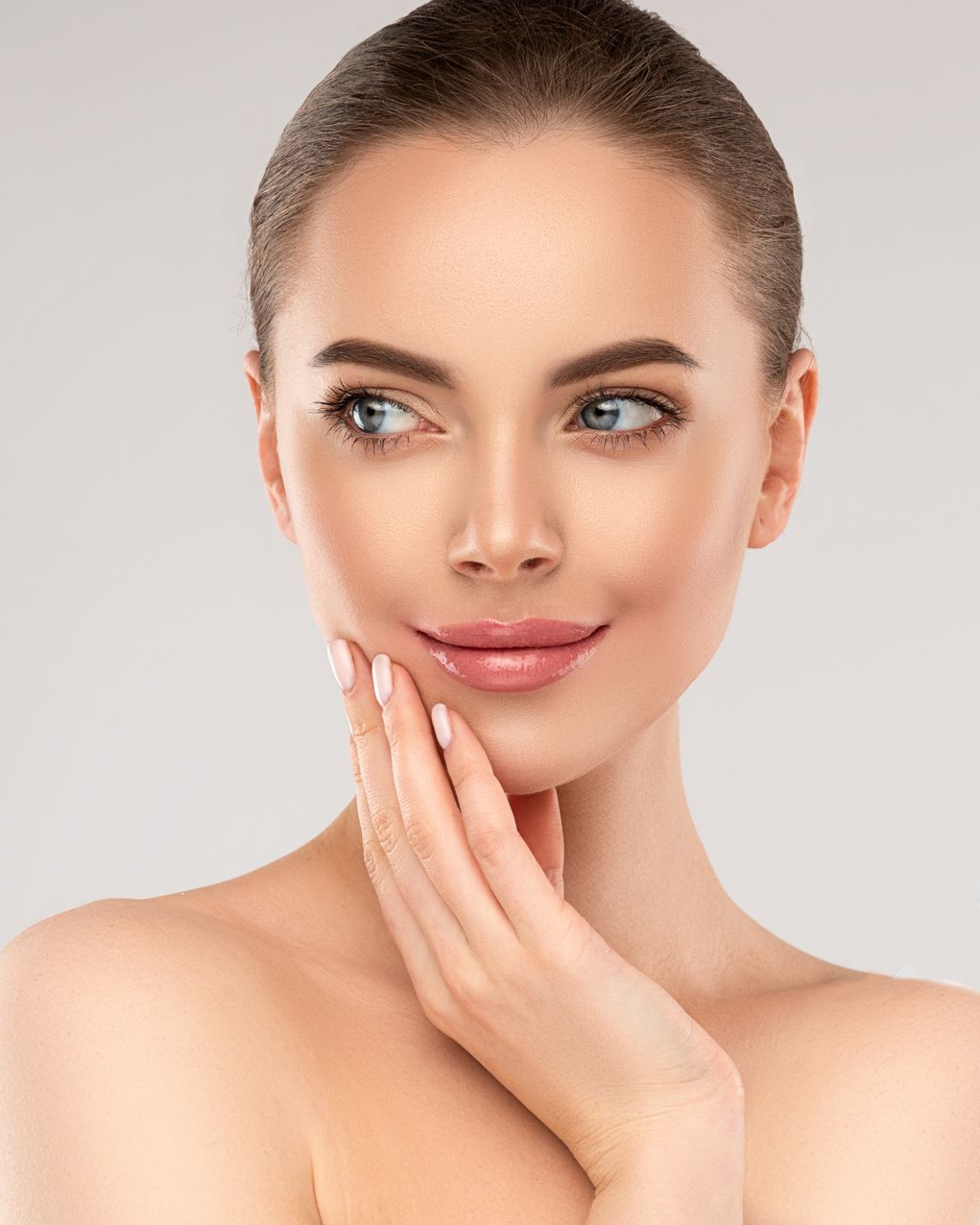 A woman is touching her face with her hand and looking at the camera.