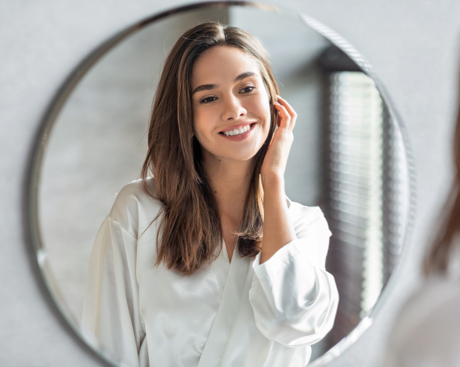 A woman is looking at herself in the mirror.