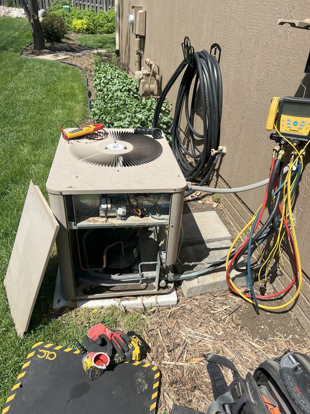 A broken air conditioner is sitting on the ground next to a hose.