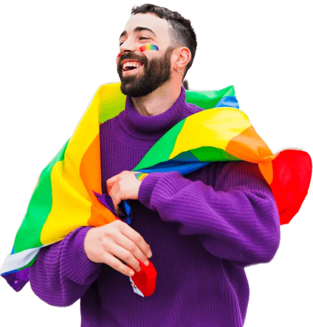 A man in a purple sweater is holding a rainbow flag over his shoulder.