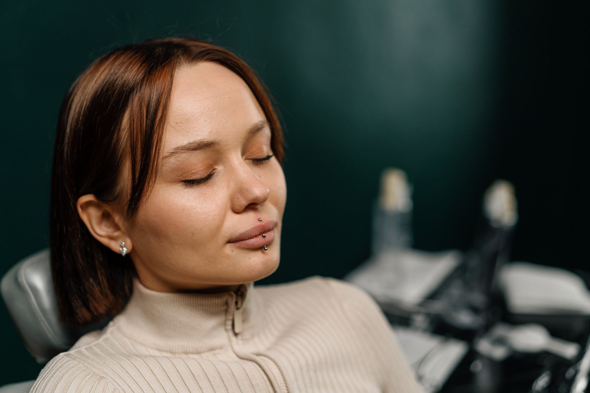 A person is sitting in a dental chair with their eyes closed.