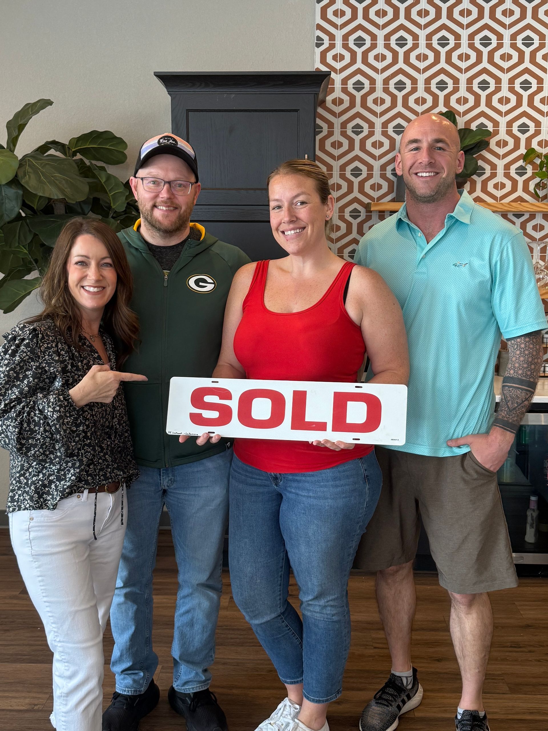 Four people smiling, holding a 