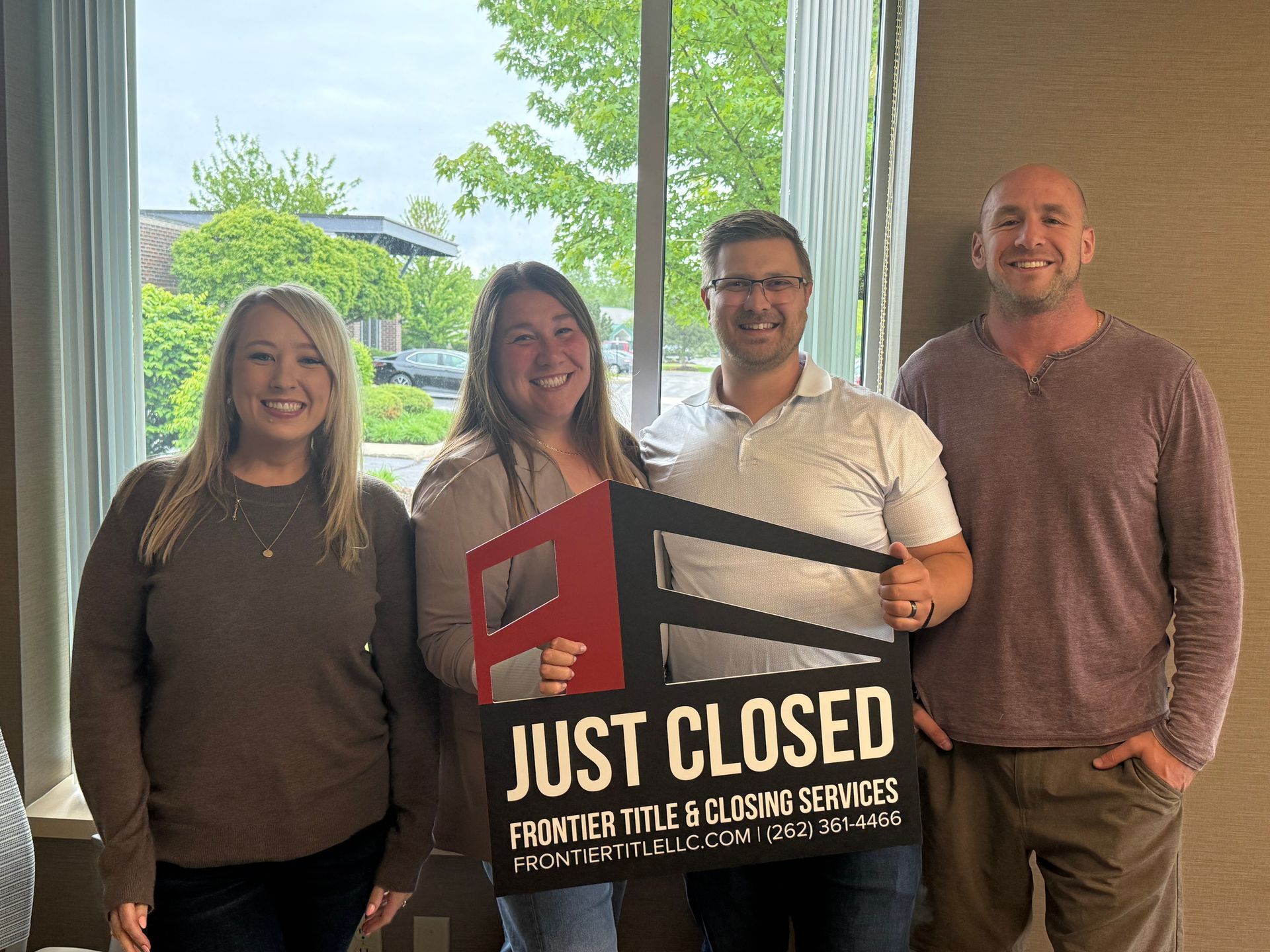 Four people celebrating a real estate closing, holding a 