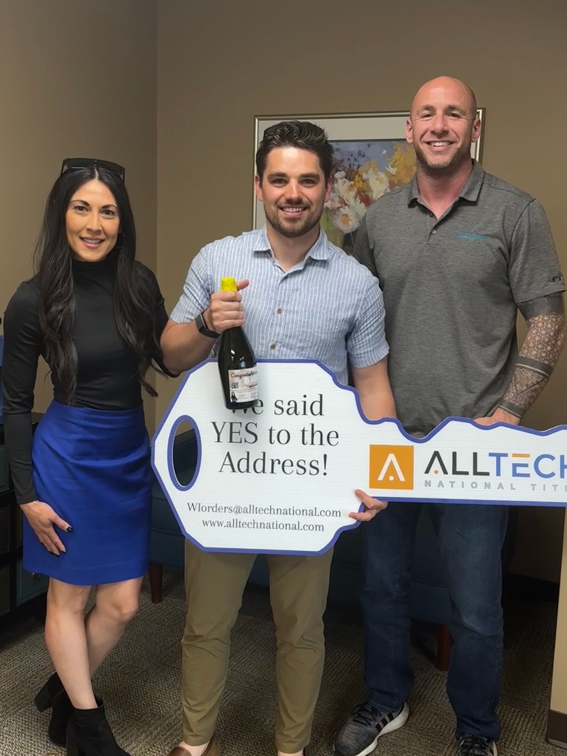 Three people holding a large key that says 