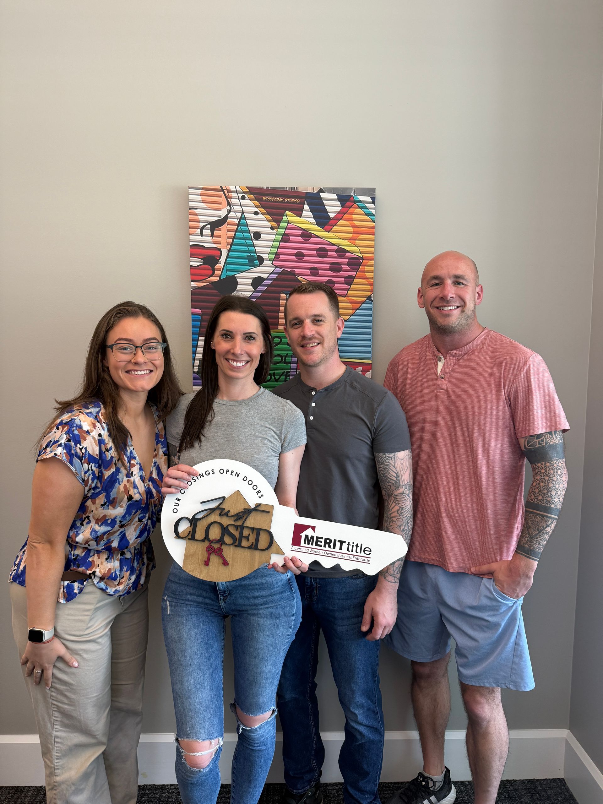 Four people pose with a large key that says 