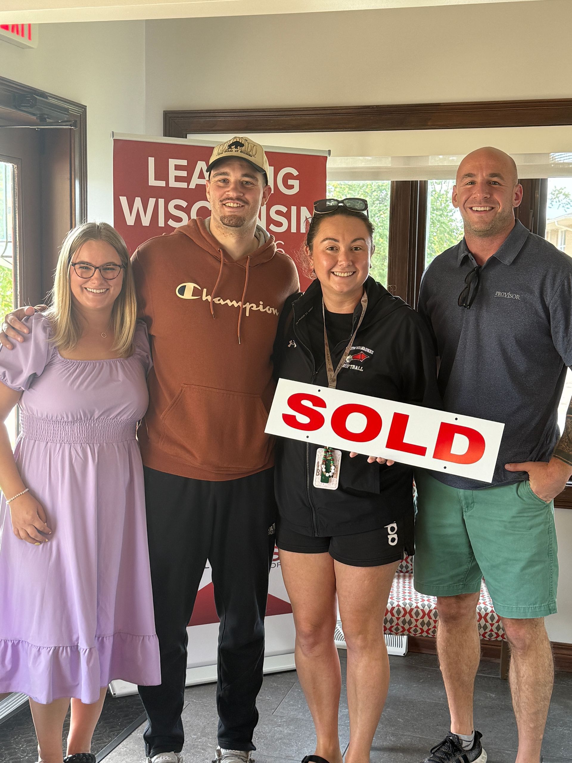 Four people smiling, posing with a 